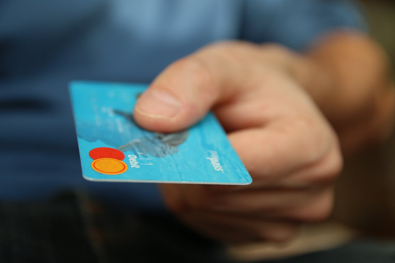 menu-02 A close-up shot of a hand offering a blue debit card for payment.