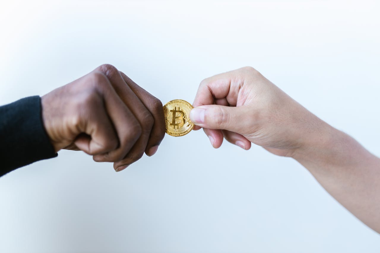 menu-05 Two hands exchanging a Bitcoin coin, symbolizing cryptocurrency transactions.